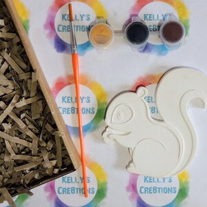K&ouml;nnte beinhalten: Eine wei&szlig;e Keramik-Eichh&ouml;rnchenfigur mit einem Malen-nach-Zahlen-Design. Das Set enth&auml;lt drei kleine Farbt&ouml;pfe, einen Pinsel und einen kleinen Beh&auml;lter mit gelber Farbe.
