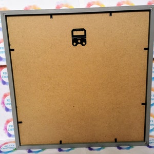 May include: The back of a gray picture frame with a black hanging hook. The frame is made of wood and has a brown cardboard backing.