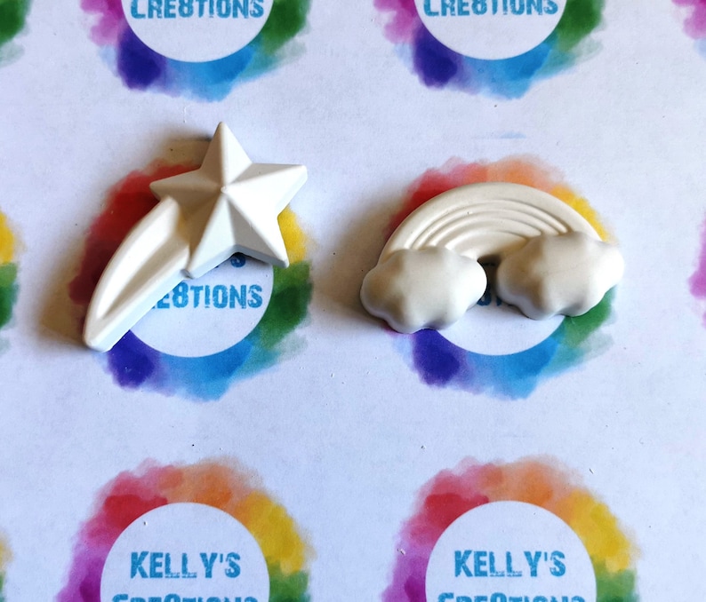 May include: Two white ceramic ornaments, a shooting star and a rainbow with clouds. The ornaments are blank and ready to be painted.