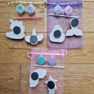 Puede incluir: Tres juegos de adornos para pintar en bolsas de organza. Cada juego incluye dos peque&ntilde;os frascos de pintura, un pincel y una variedad de adornos de cer&aacute;mica. Los adornos incluyen un unicornio, una sirena, una corona, un arco&iacute;ris y una estrella.