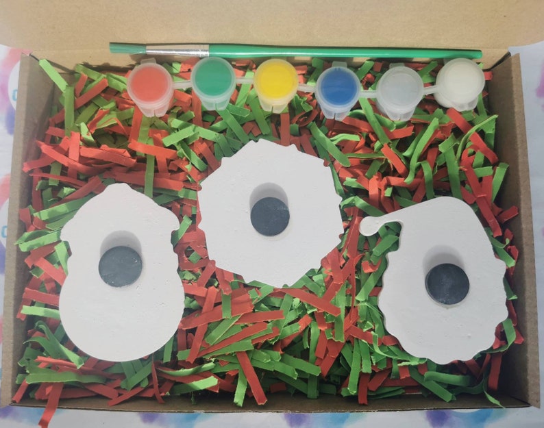 Pu&ograve; includere: Un set di tre ornamenti in ceramica bianca a forma di pupazzo di neve, una ghirlanda e Babbo Natale. Gli ornamenti hanno un foro al centro e sono circondati da carta triturata rossa e verde. Il set include cinque piccoli flaconi di vernice in rosso, verde, giallo, blu e bianco.