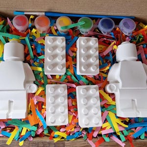 May include: A paint-your-own LEGO&reg; minifigure kit with two blank minifigures, four blank LEGO&reg; bricks, and six paint pots in red, yellow, blue, green, purple, and black.