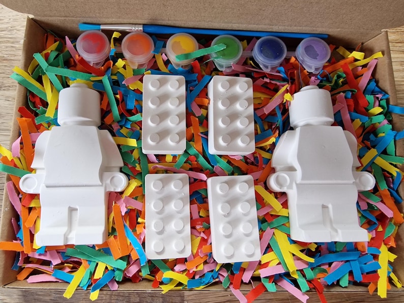 May include: A paint-your-own LEGO&reg; minifigure kit with two blank minifigures, four blank LEGO&reg; bricks, and six paint pots in red, yellow, blue, green, purple, and black.