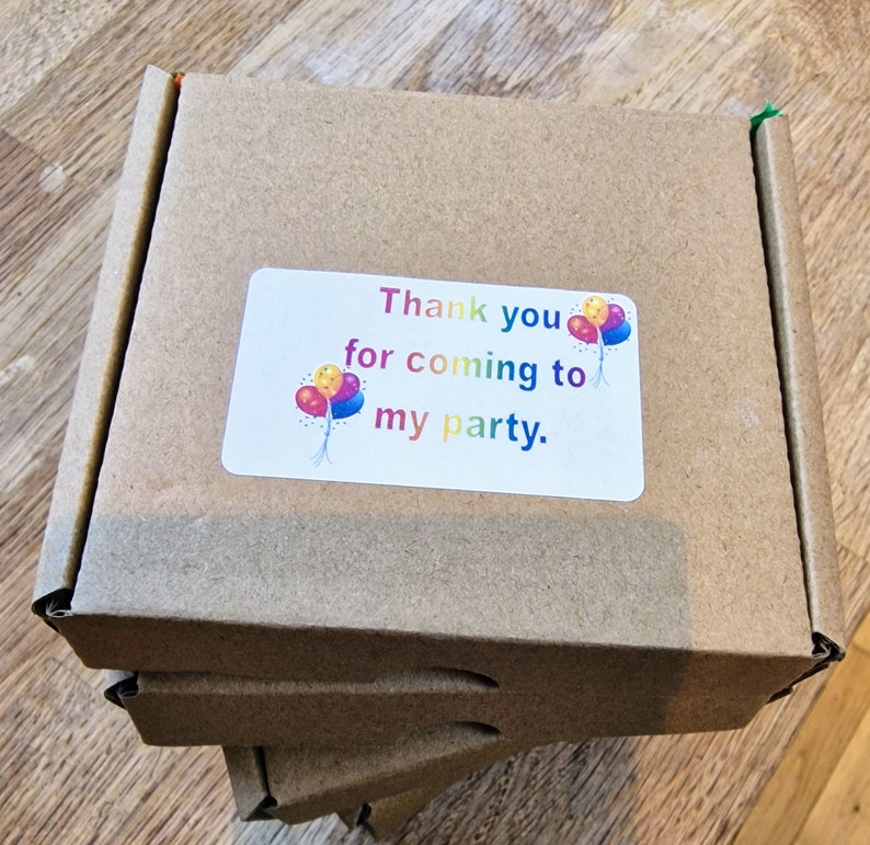 May include: A brown cardboard box with a white sticker that says "Thank you for coming to my party." The sticker has a colourful balloon graphic.