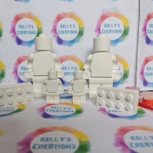 May include: A set of white unpainted figurines of Lego people and Lego bricks. The set includes two adult-sized figures, two child-sized figures, and two Lego bricks. The figures and bricks are ready to be painted.