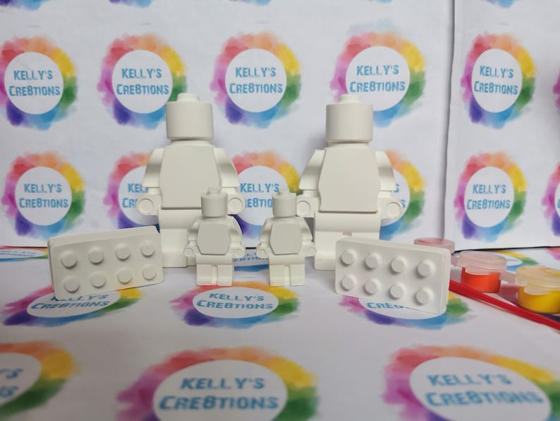 May include: A set of white unpainted figurines of Lego people and Lego bricks. The set includes two adult-sized figures, two child-sized figures, and two Lego bricks. The figures and bricks are ready to be painted.
