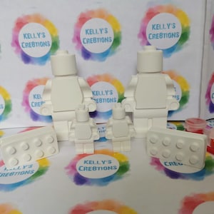 May include: A set of white, unpainted, plastic Lego-style figures, including two adults and two children, along with two rectangular bricks. The figures are ready to be painted.