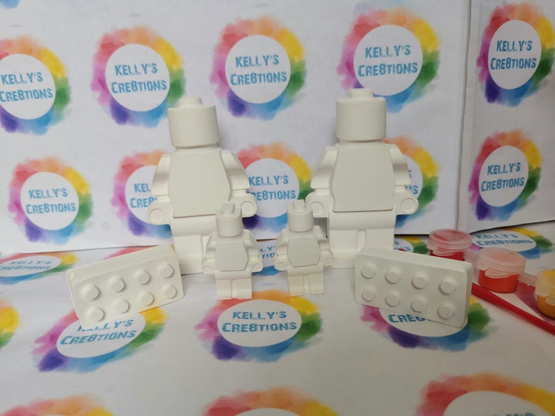 May include: A set of white, unpainted, plastic Lego-style figures, including two adults and two children, along with two rectangular bricks. The figures are ready to be painted.