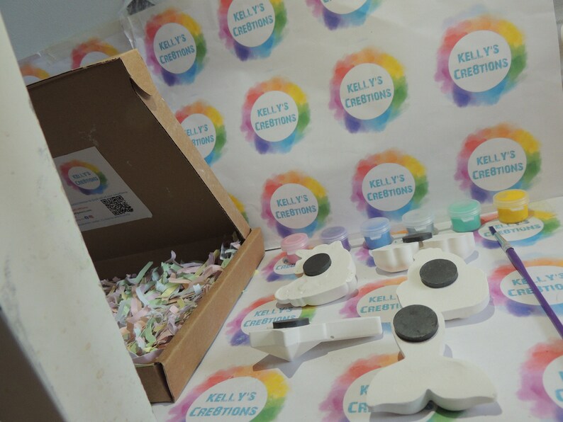Puede incluir: Un kit de manualidades con formas de unicornio, sirena y otras en cer&aacute;mica blanca con imanes en la parte posterior. El kit incluye botes de pintura de varios colores, un pincel y una caja llena de papel de seda de colores.