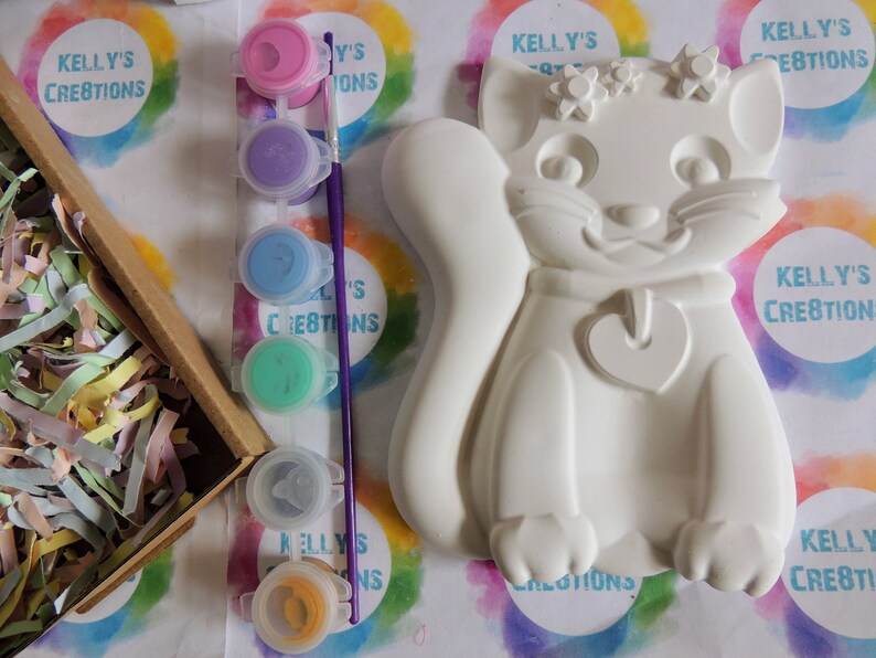 Pu&ograve; includere: Una statuetta di gatto in ceramica bianca con un ciondolo a forma di cuore e dettagli floreali. La statuetta &egrave; pronta per essere dipinta con il set di colori acrilici incluso.