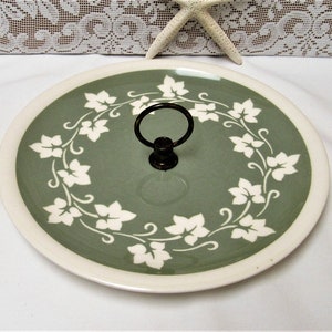 May include: A green ceramic serving tray with a white ivy design and a metal handle.