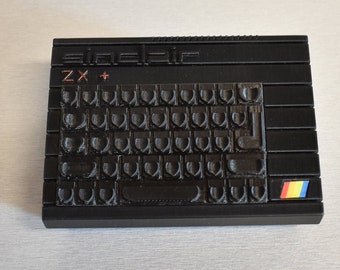 Peut inclure: Un ordinateur ZX Spectrum + noir avec un clavier et un logo arc-en-ciel.