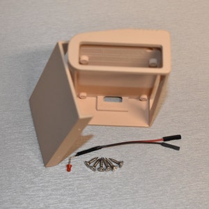 Peut inclure: Une bo&icirc;te en plastique beige avec un couvercle amovible, six vis argent&eacute;es et un fil rouge et noir avec un connecteur. La bo&icirc;te a une ouverture rectangulaire &agrave; l'avant et une petite ouverture rectangulaire sur le c&ocirc;t&eacute;.