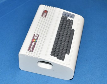 Peut inclure: Un ordinateur Commodore VIC-20 blanc avec un clavier gris et un bouton d'alimentation rouge. L'ordinateur a un logo arc-en-ciel sur le côté.