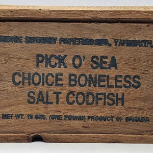 May include: A wooden box with the text "PICK O' SEA CHOICE BONELESS SALT CODFISH" printed in black. The box also has the text "NET WT. 18 OZ." and "PRODUCT OF CANADA". The box is made of wood.