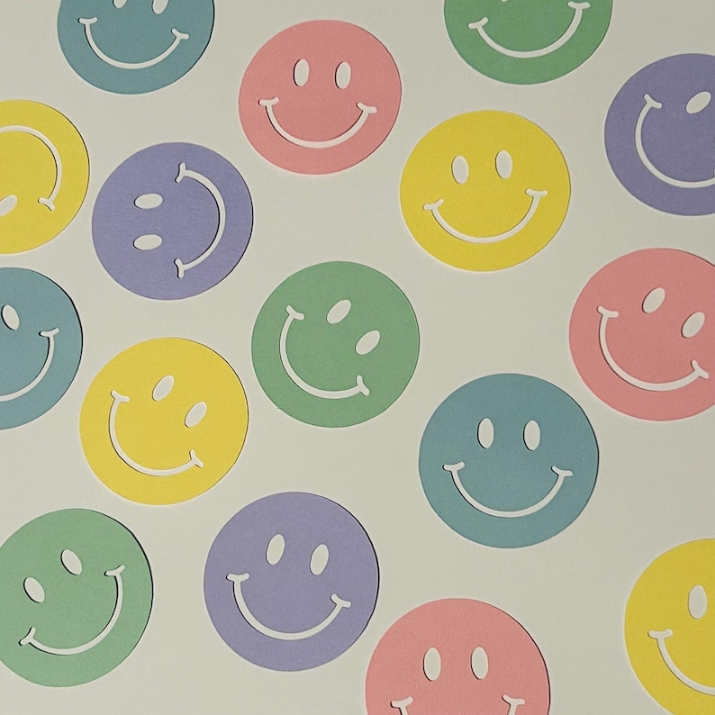 May include: A collection of colorful smiley face cutouts in various pastel shades, including pink, yellow, green, blue, and purple. Each circle features a simple, smiling face design. The cutouts are scattered on a white background.