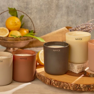 May include: Five scented candles in various colors, including beige, brown, and peach, with the word "NAYCE" printed on each candle.