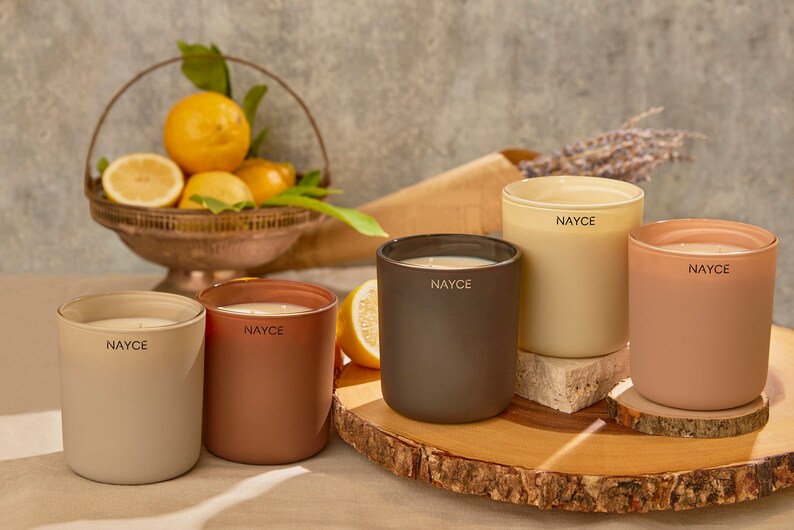 May include: Five scented candles in various colors, including beige, brown, and peach, with the word "NAYCE" printed on each candle.