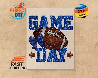 May include: A design with a brown American football, white laces, and a blue bow, with the words "GAME DAY" in glittery blue. Two brown stars are on either side. The design is on a light beige background.