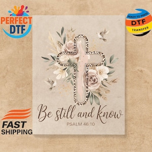 May include: A beige DTF transfer featuring a cross with a leopard print border, surrounded by floral elements and two doves. The text "Be still and know" and "PSALM 46:10" are also present.