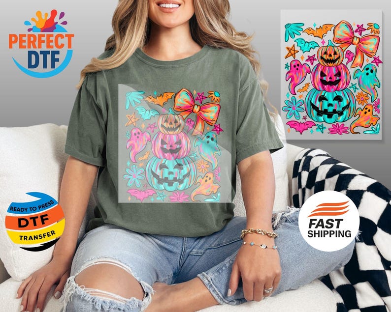 May include: Olive green t-shirt featuring a colorful Halloween design. The graphic includes stacked jack-o'-lanterns, ghosts, bows, and bats in shades of pink, teal, and orange. The shirt has the text "PERFECT DTF" and "READY TO PRESS DTF TRANSFER".