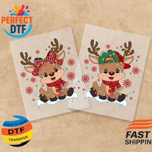 Könnte beinhalten: Zwei DTF-Transferbögen mit Cartoon-Rentieren. Jedes Rentier hat Weihnachtsbeleuchtung, einen Schal und eine Mütze. Eines trägt eine rote Schleife, das andere eine grün-rote Kappe. Rote und weiße Schneeflocken umgeben die Rentiere.