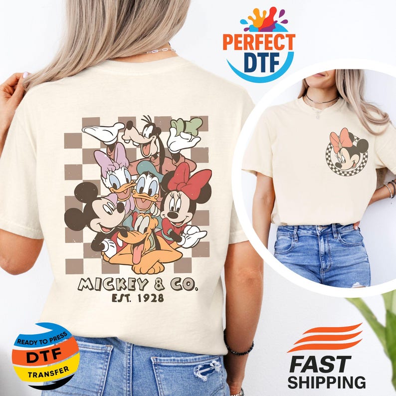 May include: Cream-colored t-shirt featuring a group of Disney characters, including Mickey Mouse, Minnie Mouse, Donald Duck, and Goofy, on a brown and white checkered background. The text "Mickey & Co. Est. 1928" is printed below the characters. A smaller image of Minnie Mouse is on the front.