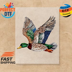 May include: A detailed illustration of a flying duck with outstretched wings, featuring a mosaic of colours including green, blue, brown, and white. The duck has a yellow beak and red accents. The image includes the text "PERFECT DTF" and "READY TO PRESS DTF TRANSFER".