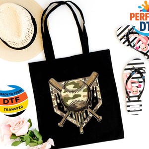 May include: Black tote bag with a baseball design featuring a camouflage pattern and dripping effect. The image includes a straw hat, black and white striped flip-flops with flamingo graphics, and DTF transfer stickers.