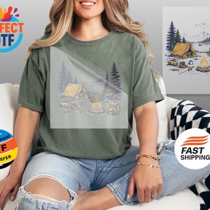 May include: Olive green t-shirt featuring a camping scene with a tent, campfire, and backpack. The design is printed on the front of the shirt. The shirt is paired with blue jeans. The image also includes the text "PERFECT DTF" and "READY TO PRESS DTF TRANSFER".