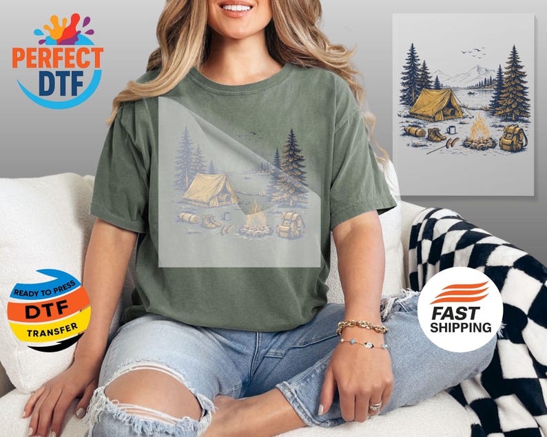 May include: Olive green t-shirt featuring a camping scene with a tent, campfire, and backpack. The design is printed on the front of the shirt. The shirt is paired with blue jeans. The image also includes the text "PERFECT DTF" and "READY TO PRESS DTF TRANSFER".