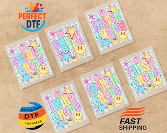 May include: Five rectangular DTF transfers featuring school grade levels from Pre-K to Fourth Grade. Each design includes colorful, patterned text, a yellow smiley face, a pink apple, a blue star, and a small yellow pencil holder.