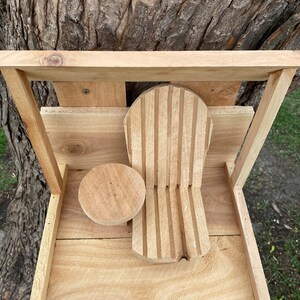 May include: A wooden bird feeder with a small, round perch and a larger, slatted perch. The feeder is mounted on a tree trunk.