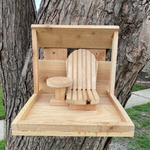 May include: A wooden bird feeder with a small table and a chair, mounted on a tree trunk.