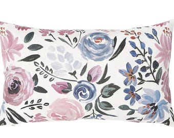 Op de afbeelding: Een wit kussen met een bloemenpatroon met roze, blauwe en grijze bloemen op een witte achtergrond.