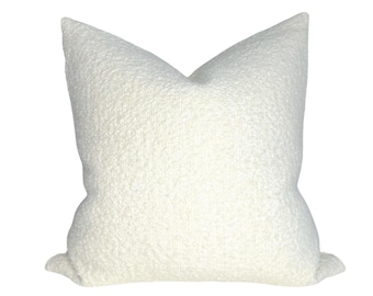 May include: A white, fluffy pillow with a textured surface. The pillow is square-shaped and has a simple design.