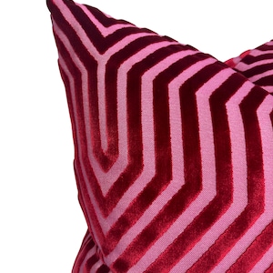 May include: A red and pink chevron patterned throw pillow with a soft velvet texture.