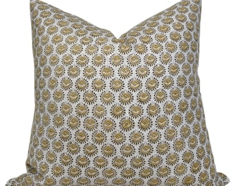 May include: A square throw pillow featuring a repeating pattern of small, stylized golden-brown and dark brown floral motifs printed on a light gray, textured fabric background. The pillow has a plump, filled shape with pointed top corners.