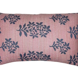 May include: A rectangular pink throw pillow with a floral pattern in navy blue. The pillow has a subtle textured fabric.
