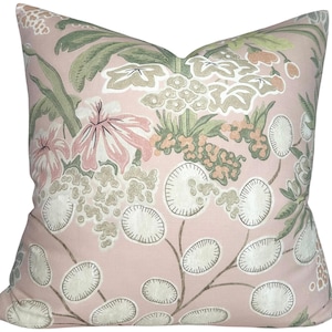 May include: A square cushion with a floral design. The cushion has a pale pink base, adorned with a repeating pattern of flowers and leaves in green, white, and pink. The cushion is square in shape.