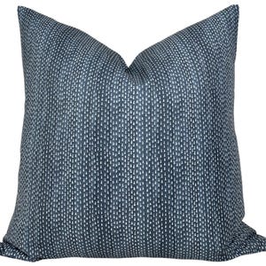 May include: A square scatter cushion featuring a deep navy blue fabric base with a repeating pattern of small, vertical white dashes arranged in columns. The cushion has a soft, plump appearance with a distinct crease at the top centre.