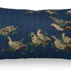 May include: Rectangular cushion featuring a dark blue fabric with a repeating pattern of birds. The birds are depicted in beige, brown, green, and red. This decorative cushion is designed for home decor and interior design.