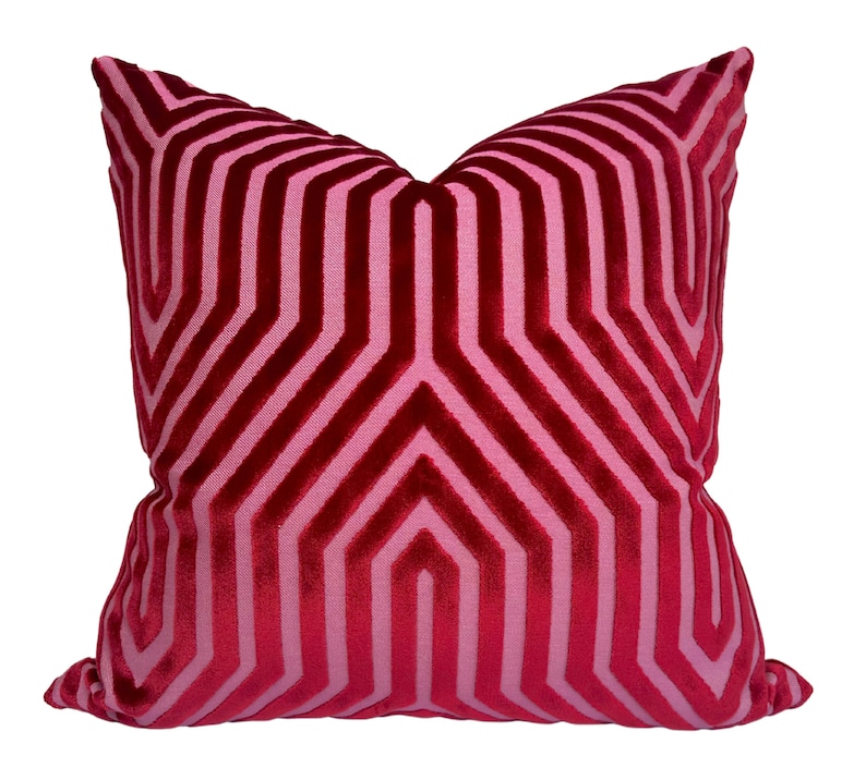 May include: A red and pink geometric patterned throw pillow with a velvet texture.