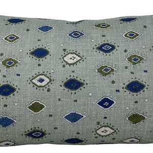 May include: A rectangular throw pillow with a light gray base fabric featuring a repeating pattern of small, diamond-shaped motifs in shades of navy blue, olive green, and white. The pillow has a textured, woven appearance with clean edges.