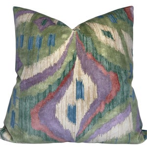 Könnte beinhalten: Ein dekoratives Kissen mit einem abstrakten Muster in Grün, Lila, Blau und Rot. Das Kissen ist aus einem weichen, plüschigen Stoff.