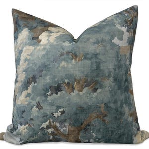 May include: A square decorative pillow with a nature-inspired design. The pillow features a watercolor-style print of a tree canopy in shades of blue, brown, and cream. The pillow has a soft, textured appearance, suitable for home decor.