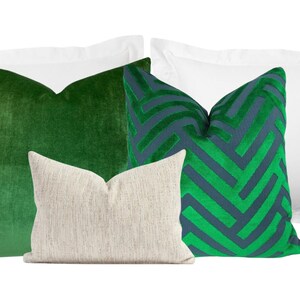 May include: Four decorative throw pillows, two white, one green velvet, one green and blue geometric pattern.
