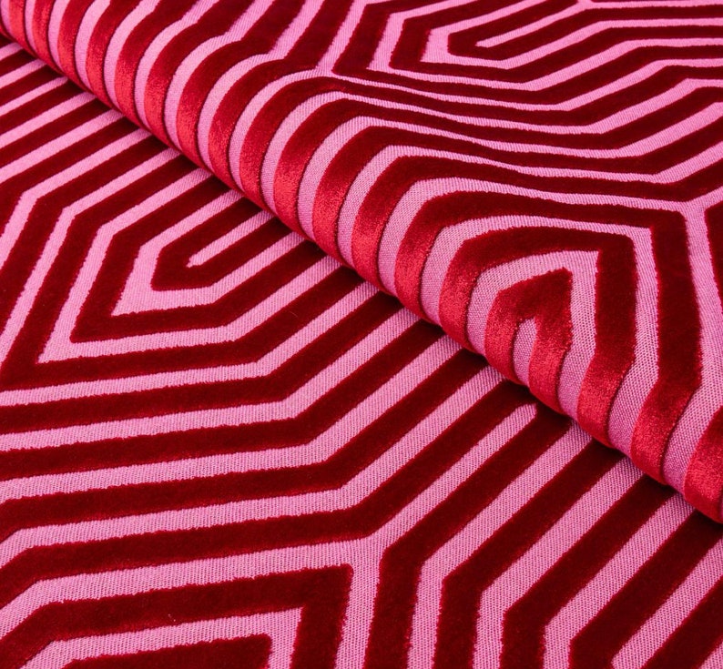 May include: Red and pink fabric with a geometric pattern of overlapping stripes and hexagons.