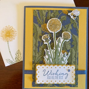 May include: A yellow and blue greeting card with a dandelion design and the text "Wishing you all the best".