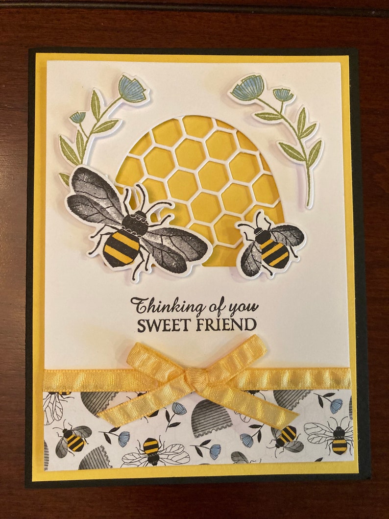 K&ouml;nnte beinhalten: Eine handgemachte Gru&szlig;karte mit einem gelben Wabenmuster und zwei Bienen. Die Karte hat ein gelbes Band und den Text "Thinking of you Sweet Friend".